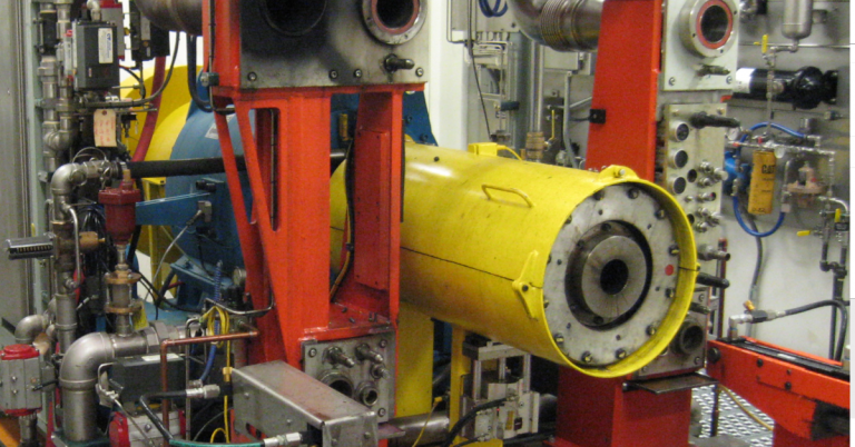 Industrial test stand with a large yellow torque and load device coupled to red rotating machinery