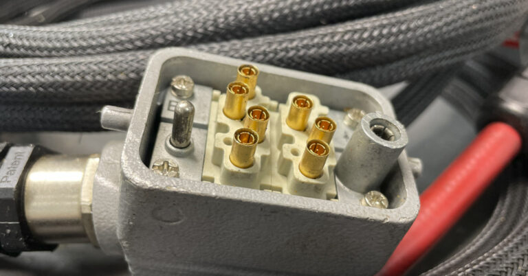 Close-up of an industrial multi-pin connector on a shielded cable harness