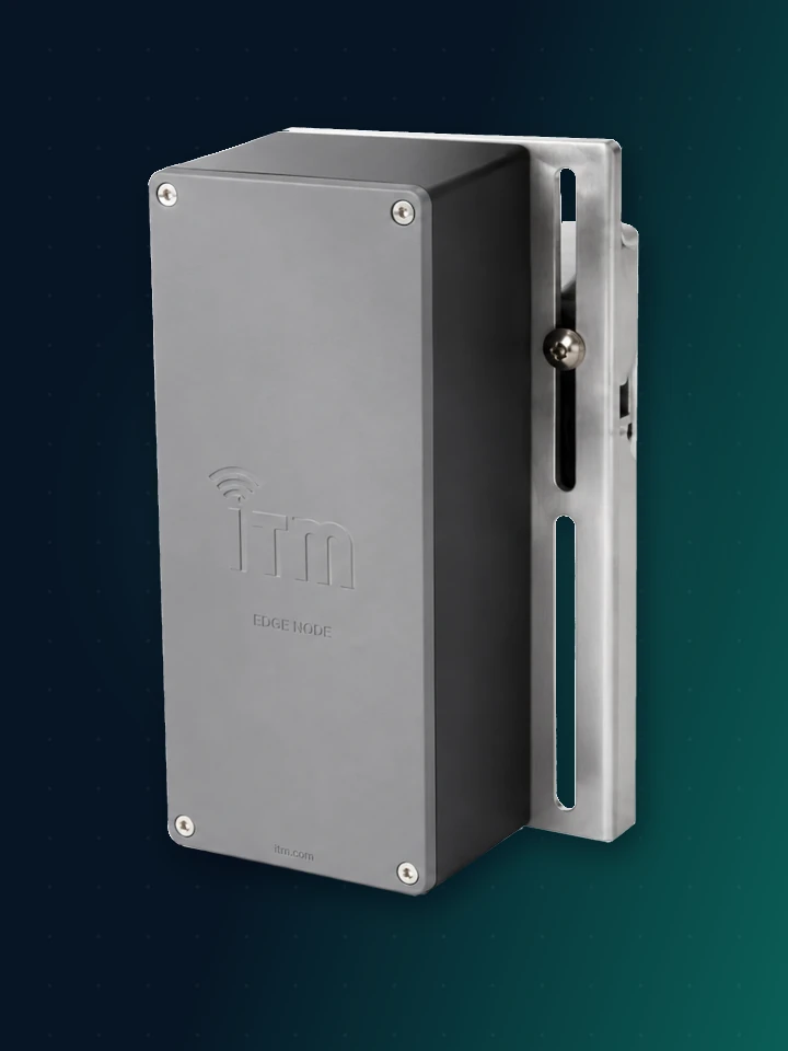 ITM Wireless Sootblower Lance Temperature Node — a dark graphite sealed enclosure with an embossed ITM mark and corner screws, on a slotted stainless steel mounting bracket